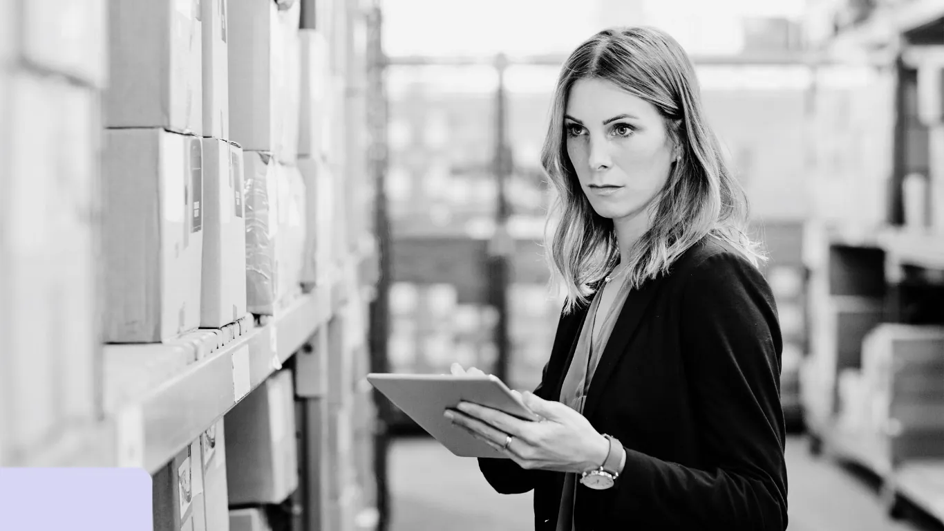 Woman inspecting warehouse inventory on tablet.