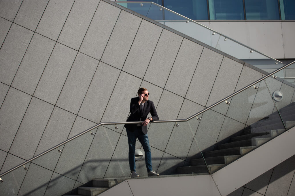 Person standing on modern staircase with sunglasses.