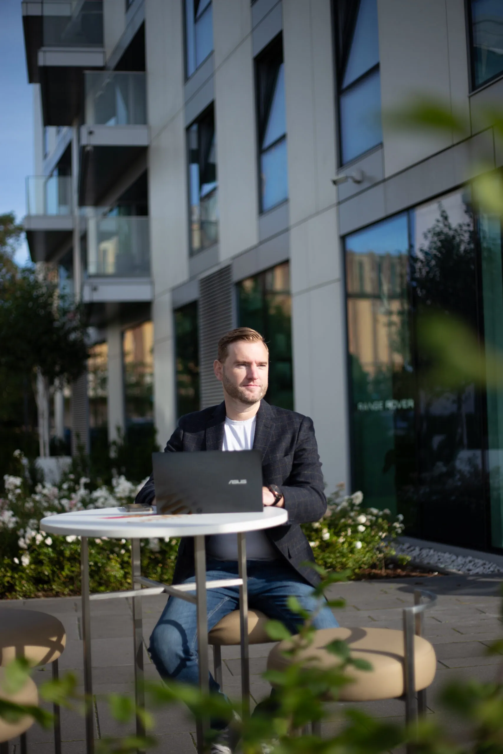 Man working on laptop outside modern building.