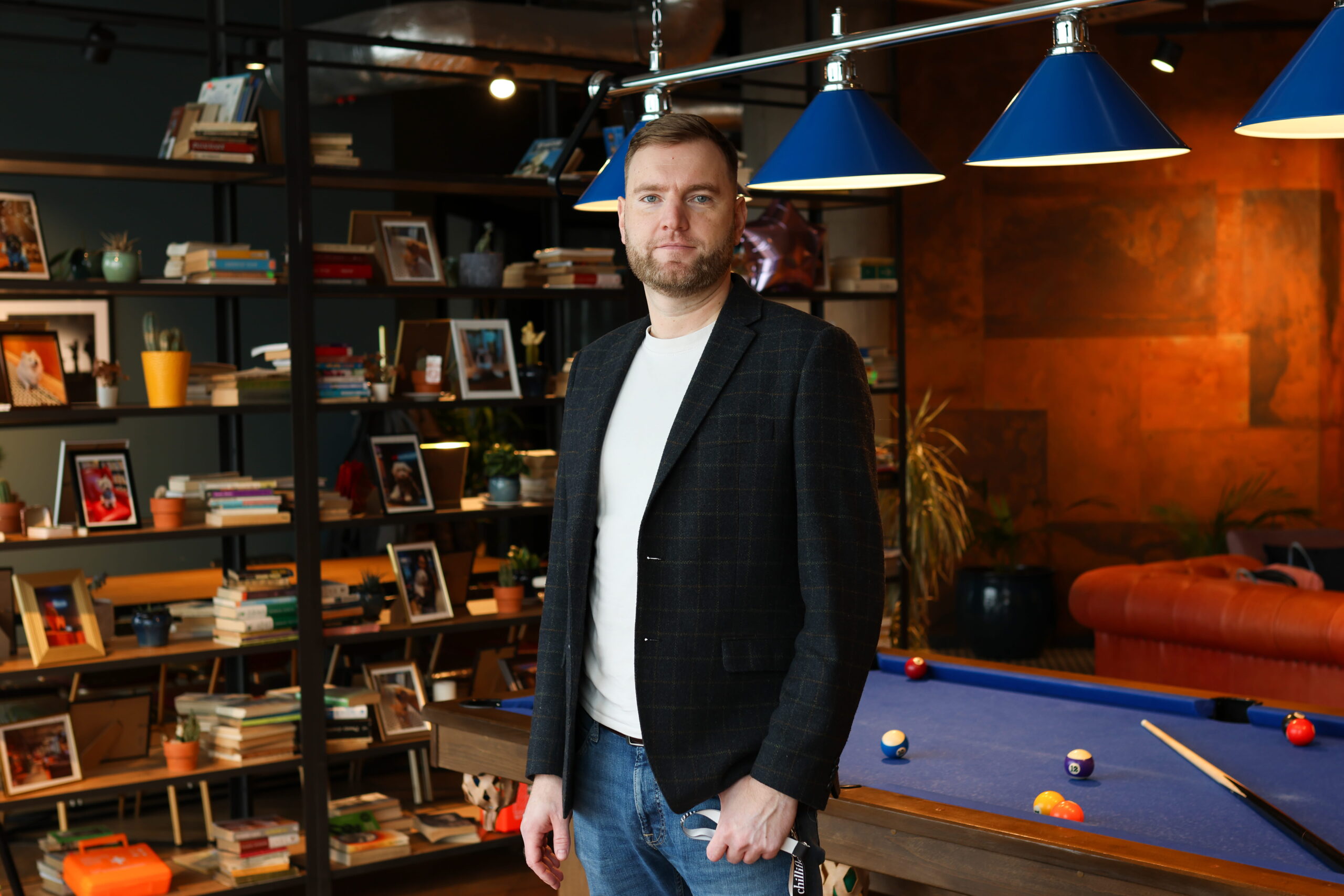Man in library near a pool table, stylish interior.