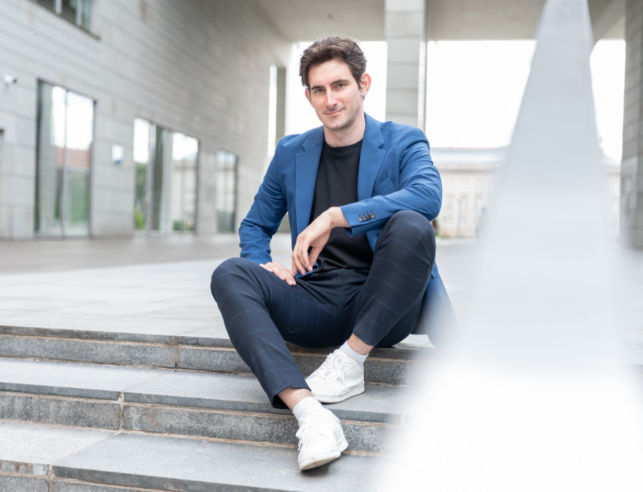 Man in blue jacket sitting on outdoor steps.