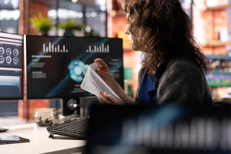 Woman analysing data on computer screens in office.